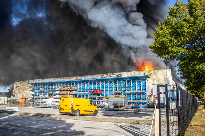 Breed overzicht van een zeer grote industriebrand met zware rook in Udenhout